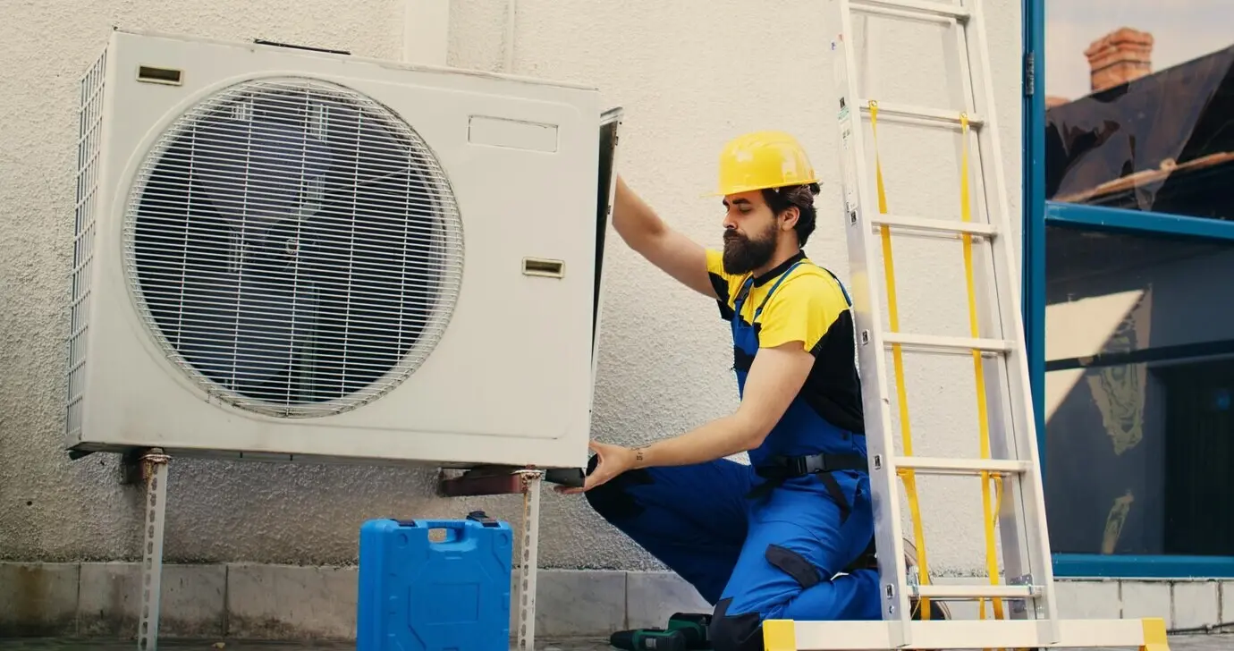 A worker works on an air conditioner.