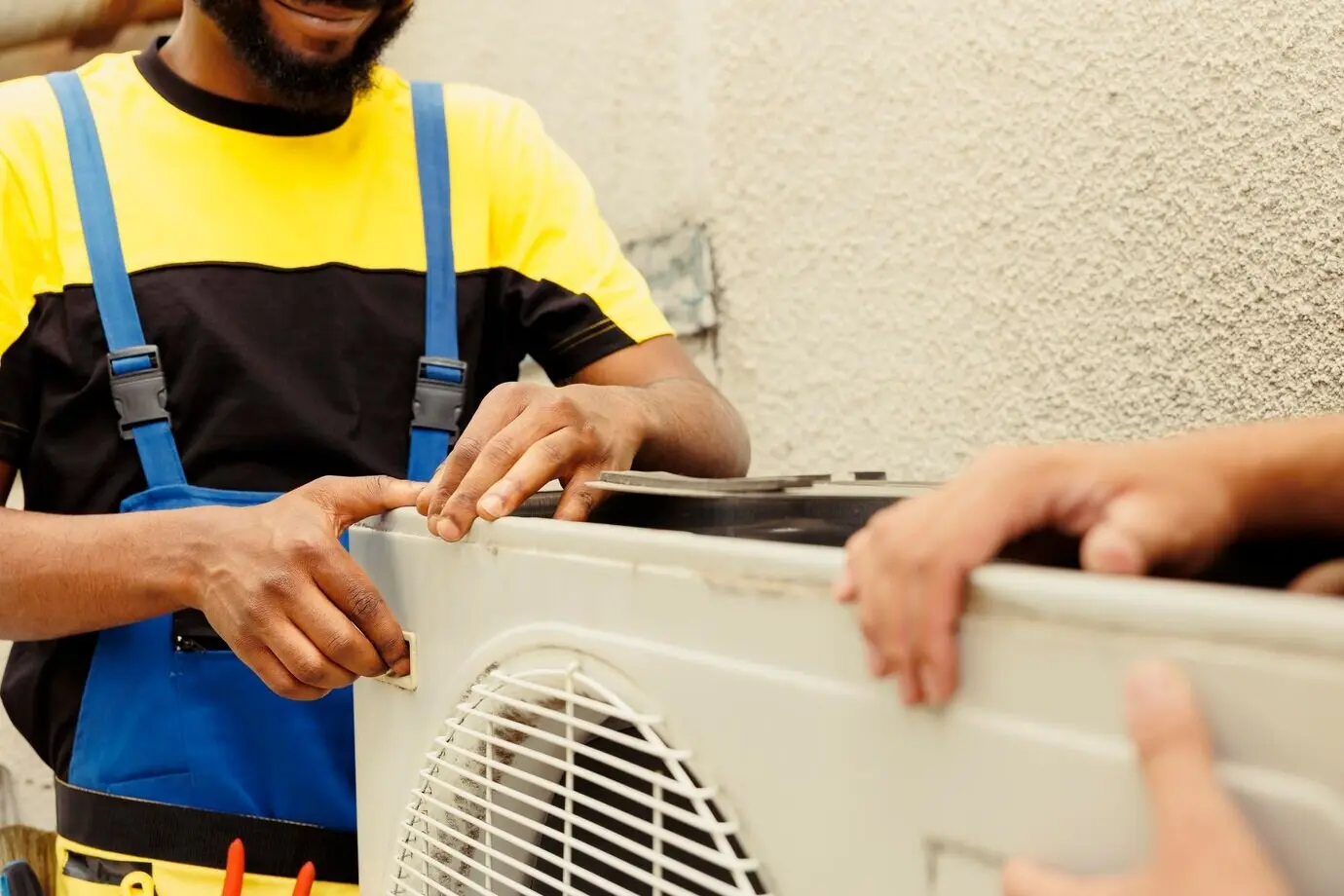Trained engineer and certified technician opening up an old, faulty HVAC system to replace it with a new high-performance outdoor air conditioner after draining the refrigerant and replacing the ductwork.